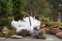 Weihnachtsdeko mit Christbaumkugeln, Federn und Zapfen auf Gartentisch