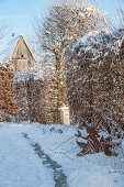 Verschneiter winterlicher Garten mit Rankbogen und Vogelhaus