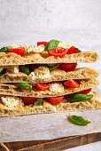 Stacked pinsa with tomatoes, mozzarella, basil and olive oil