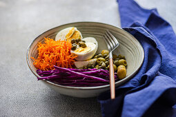 Bowl mit gekochten Eiern, Kapern, Oliven, Rotkohl und Möhren (Keto-Küche)