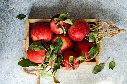 Wooden box with red apples on concrete table