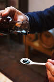 Pouring balsamic vinegar onto a spoon (tasting)