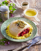 Yeast dumpling with raspberry filling, vanilla sauce and pistachios