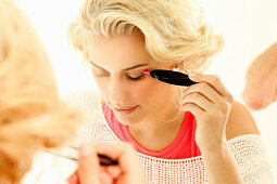 Blonde woman uses an eyelash applicator