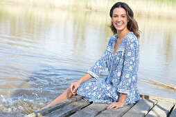 Brunette woman sitting on a wooden pier by the lake