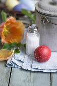 Red Easter egg with broken shell, salt shaker and tulip