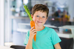 Boy in turquoise blue T-shirt with carrot at the table
