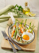 Fried egg with spring carrots and asparagus in herb sauce