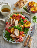 Chicken salad with grilled peaches, ham and rocket salad