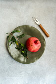 Ripe pomegranate with leaves on a plate