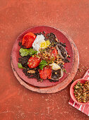 Oven-baked tomatoes on beluga lentils with poached egg and spice crumble