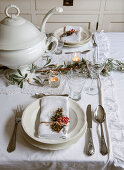 Christmas table setting in white, garland and soup tureen in the center