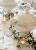 Gedeckter Weihnachtstisch in Weiß, Girlande und Suppenterrine in der Mitte