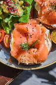 Person eating a salmon bagel sandwich