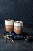 Three types of chocolate mousse layered in glasses