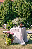 Gedeckter Tisch mit Blumen und Gugelhupf im sommerlichen Garten