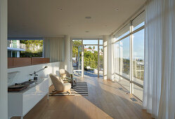 Sunlit seating area with record player in front of floor-to-ceiling windows