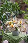 Blumenstrauß aus Felsenbirne, Tulpen, Narzissen 'Poeticus' und 'Tahiti' in Vase auf Gartenstuhl mit Decke
