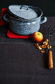 Enamelled casserole, apple, walnuts and potato masher