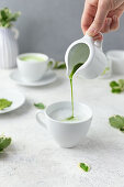 Pouring matcha into foamed coconut milk