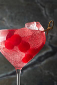 Red cocktail with ice cubes and cherries