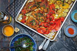 Chicken drumsticks with potatoes and tomatoes from the tray, served with gremolata