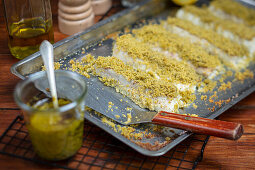Fish fillet with herb crust on a baking tray