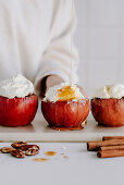 Baked apples with nut filling, garnished with cream and maple syrup