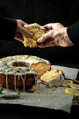 Vegan lemon wreath cake with rosemary, two hands grabbing a piece of cake