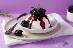 Mini pavlova topped with blackberries, cream and blackberry sauce