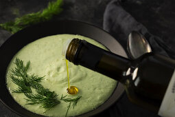 Kalte Gurkensuppe mit Dill wird mit Olivenöl beträufelt