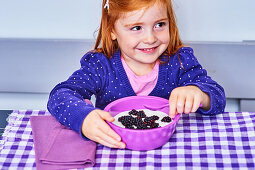 Kleines Mädchen isst Joghurt mit frischen Brombeeren