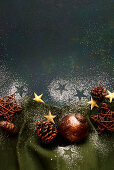 Cones, Christmas baubles, stars and icing sugar decoration on a green background