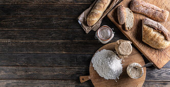 Mehl, Brot und Gläser mit Roggensauerteig