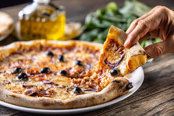Pizza mit Speck, Zwiebeln und schwarzen Oliven