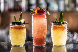 Mai Tai cocktails in Hawaiian glasses, garnished with pineapple, blueberries and strawberries