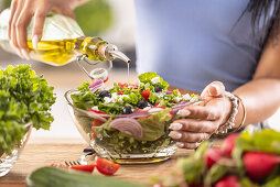Frau gießt Olivenöl über gesunden Salat