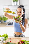 Woman pours olive oil over healthy salad