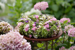 Herbstkranz mit Hortensien (Hydrangea), Sedum und Rosen auf Gartentisch