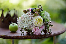 Spätsommerstrauß mit Rosen, Dahlien (Dahlia) und Beeren auf Gartentisch