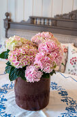 Hortensien (Hydrangea) in rustikaler Vase auf Tisch