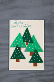 DIY-Weihnachtskarte mit Filz-Tannenbäumen auf grauem Holzuntergrund