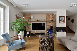 Living room with fireplace, brick wall and unusual glass table