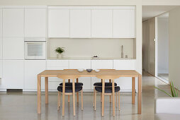 Modern kitchen with white built-in cabinets and wooden table in a new building