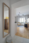 Bright hallway with mirror leads into living room with sofa and armchair