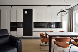 Modern kitchen in black and white with dining table and colorful designer chairs