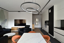 Modern living and dining room with ring pendant light and black and white kitchen unit