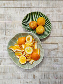 Geschälte Orangen und Orangenschalen auf Keramiktellern