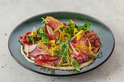 Carpaccio vom geräucherten Rind mit Wildkräutern, Blüten und Parmesanchips