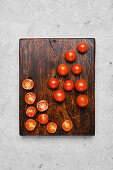 Whole and halved cherry tomatoes on a chopping board